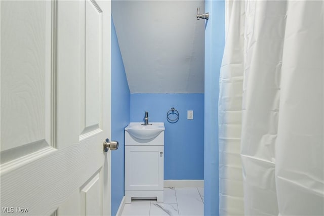 full bathroom featuring baseboards, lofted ceiling, marble finish floor, and vanity