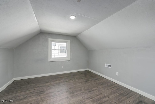 additional living space with dark wood-type flooring, baseboards, and lofted ceiling