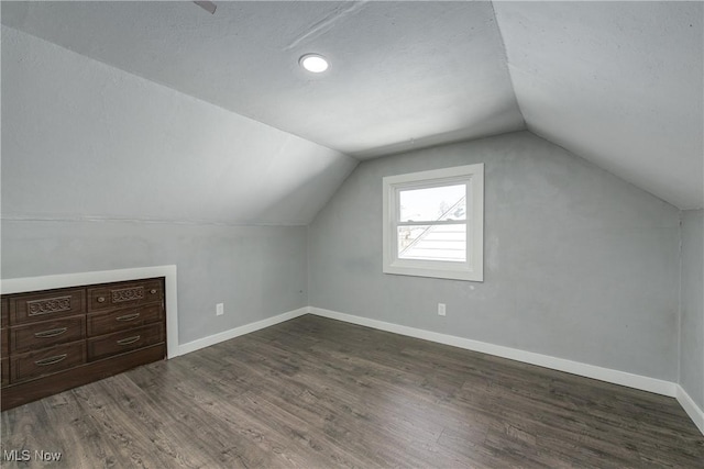 additional living space with vaulted ceiling, dark wood-style floors, and baseboards