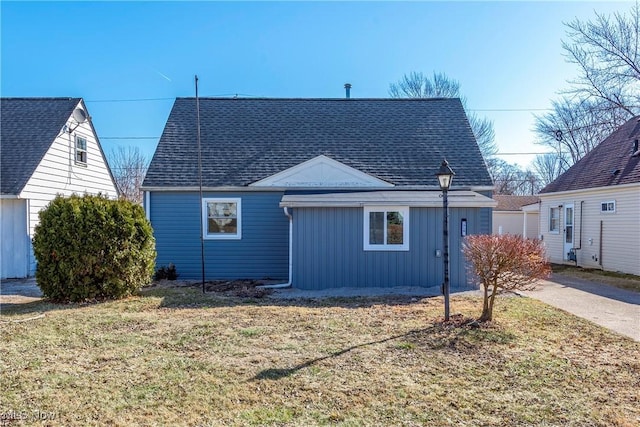 view of side of property with board and batten siding, a yard, and roof with shingles