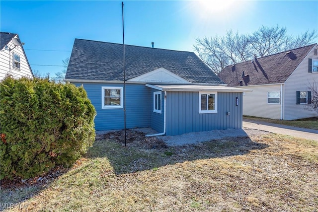 rear view of house with board and batten siding and a shingled roof