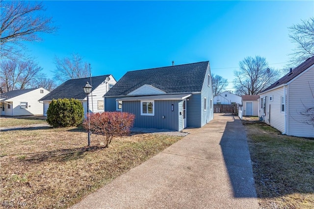 view of front of property featuring board and batten siding, a front yard, driveway, and roof with shingles