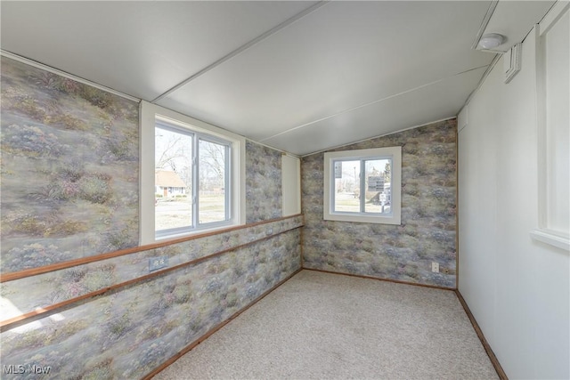 carpeted empty room with vaulted ceiling and baseboards