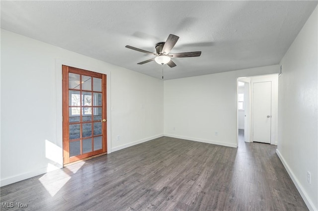 empty room with a healthy amount of sunlight, baseboards, dark wood-type flooring, and a ceiling fan