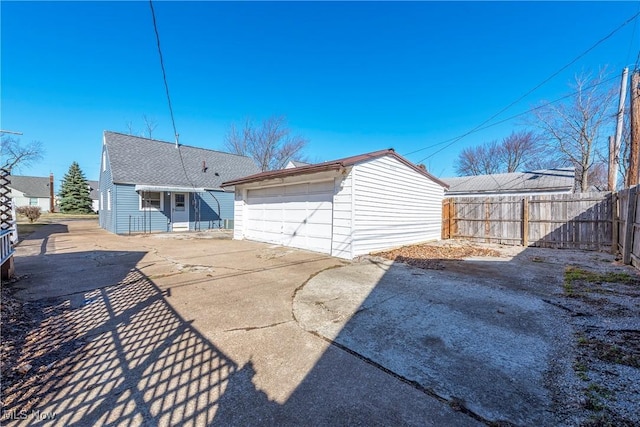 back of house with a detached garage, fence, and an outdoor structure