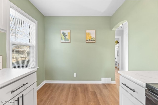 dining room with visible vents, arched walkways, light wood-style floors, and baseboards