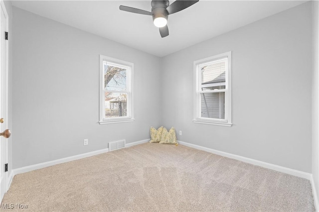 carpeted spare room featuring visible vents, baseboards, and ceiling fan