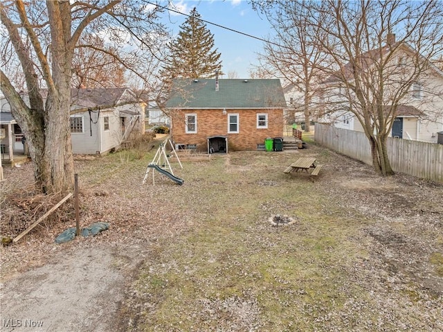 rear view of house featuring brick siding and fence