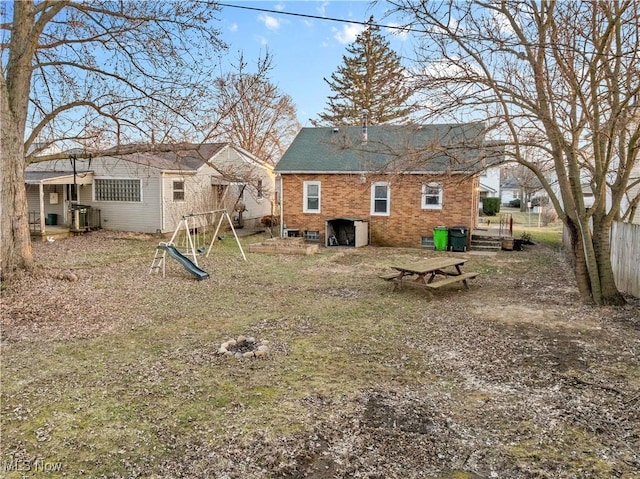 back of property featuring brick siding, a playground, and fence