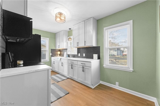 kitchen featuring light wood-style floors, backsplash, a healthy amount of sunlight, and white cabinetry