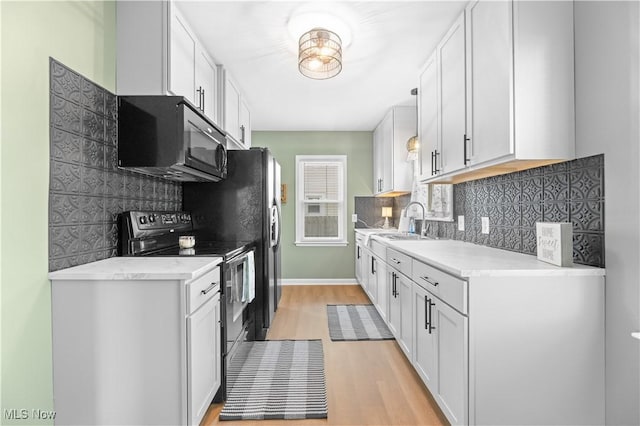 kitchen with electric range oven, light countertops, light wood-style floors, black microwave, and backsplash