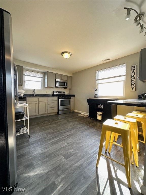 kitchen featuring dark countertops, visible vents, gray cabinetry, stainless steel appliances, and dark wood-style flooring