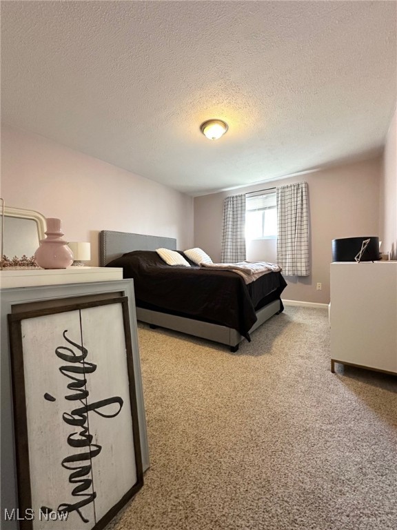 carpeted bedroom featuring a textured ceiling and baseboards