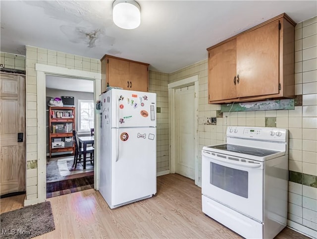 kitchen featuring brown cabinetry, white appliances, tile walls, and light wood-style floors