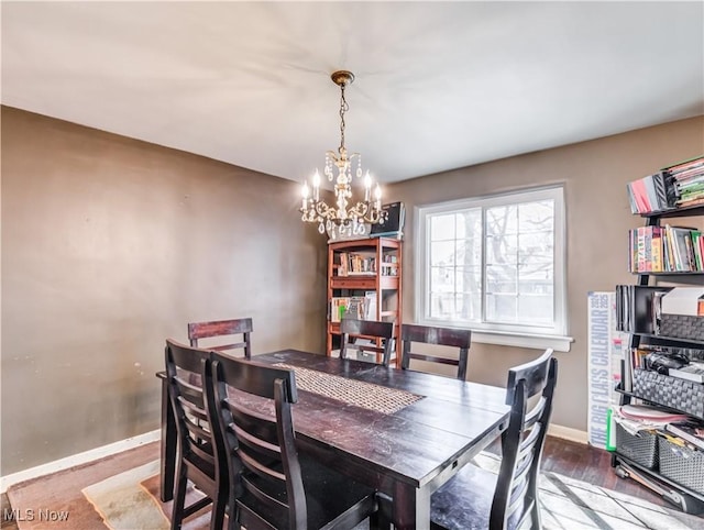 dining room with a chandelier, baseboards, and wood finished floors