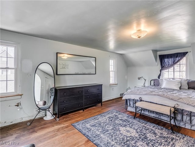 bedroom featuring lofted ceiling, wood finished floors, visible vents, and baseboards