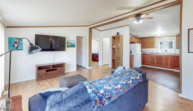 living area with light wood-style flooring, crown molding, lofted ceiling with beams, and a ceiling fan