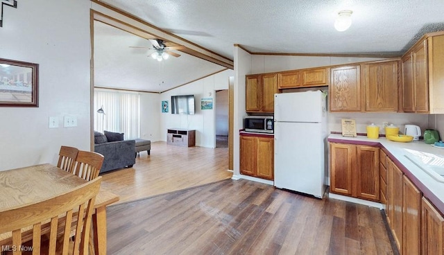 kitchen with a ceiling fan, lofted ceiling with beams, freestanding refrigerator, light countertops, and stainless steel microwave