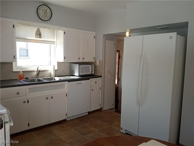 kitchen with white appliances, a sink, white cabinets, dark countertops, and backsplash