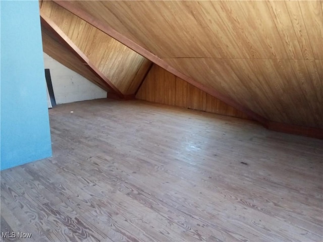 bonus room featuring lofted ceiling, wood finished floors, and wood walls