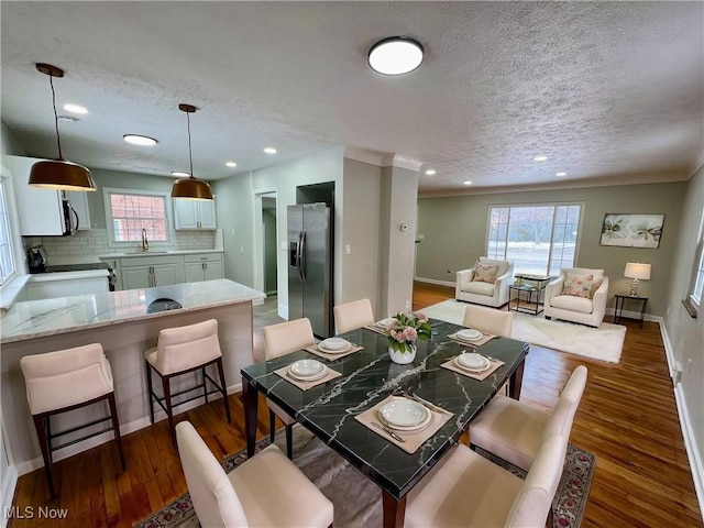 dining space featuring baseboards, a textured ceiling, and dark wood finished floors