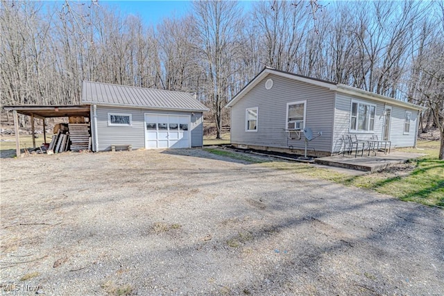 view of side of home with a carport, metal roof, an outbuilding, and driveway