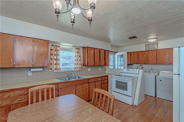 kitchen featuring independent washer and dryer, white electric stove, light wood-style flooring, a sink, and brown cabinets