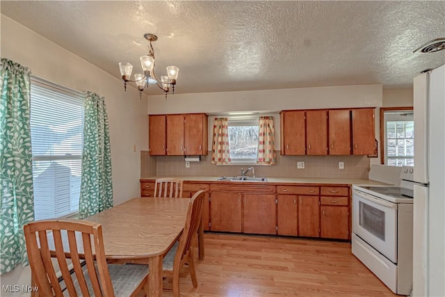 kitchen with white electric range oven, brown cabinetry, light countertops, and a sink