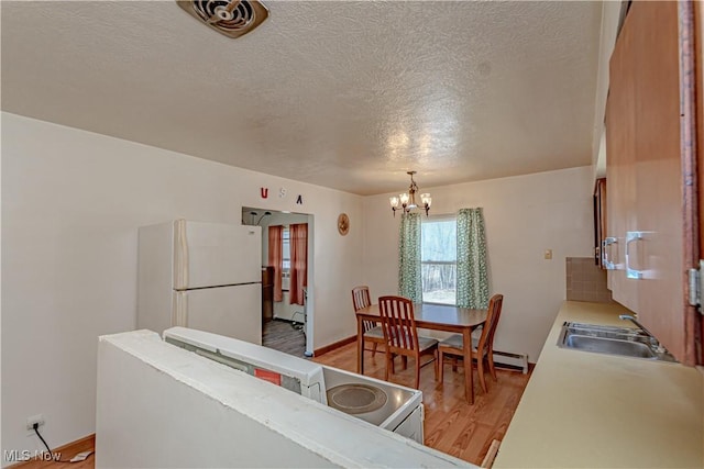 dining room featuring a notable chandelier, light wood-style flooring, a textured ceiling, and baseboards