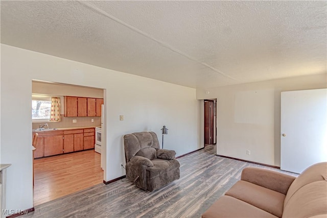 living room with baseboards, light wood-style floors, and a textured ceiling