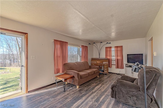 living room featuring dark wood-style floors, a textured ceiling, and baseboards