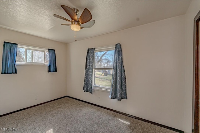 empty room with ceiling fan, carpet flooring, baseboards, and a textured ceiling