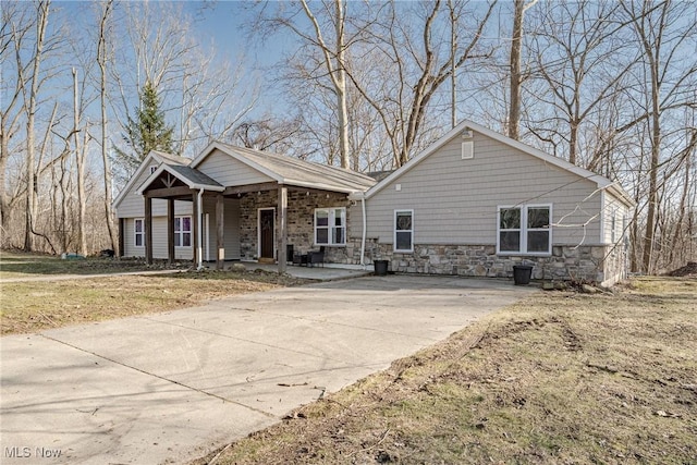 view of front of property with stone siding, a porch, and concrete driveway