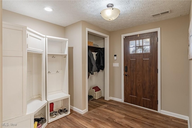 mudroom featuring a textured ceiling, wood finished floors, visible vents, and baseboards