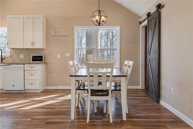 dining room featuring a barn door, lofted ceiling, a healthy amount of sunlight, and wood finished floors