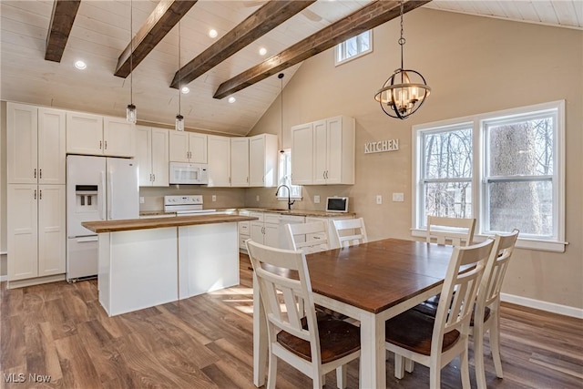 dining area with beam ceiling, a notable chandelier, and wood finished floors