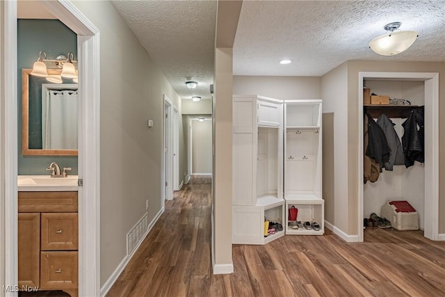 mudroom featuring dark wood finished floors, baseboards, visible vents, and a textured ceiling