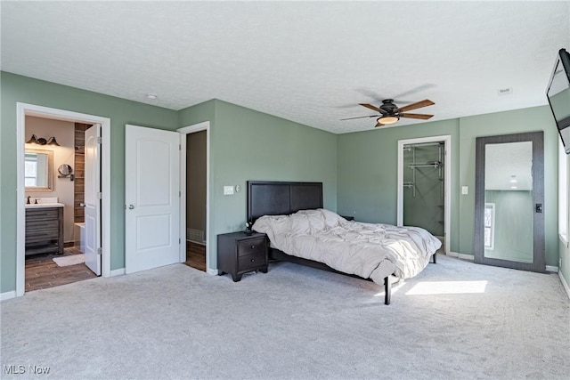 carpeted bedroom featuring baseboards, ceiling fan, a closet, a textured ceiling, and a walk in closet