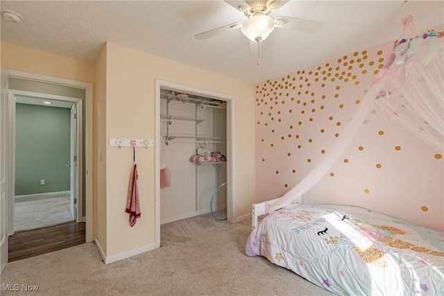 bedroom featuring light carpet, a ceiling fan, a textured ceiling, a closet, and baseboards