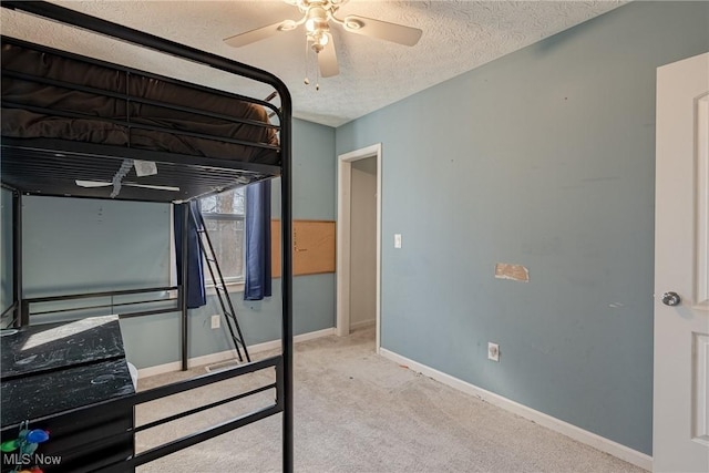 unfurnished bedroom with ceiling fan, baseboards, carpet floors, and a textured ceiling