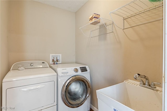 clothes washing area with a sink, separate washer and dryer, laundry area, and a textured ceiling