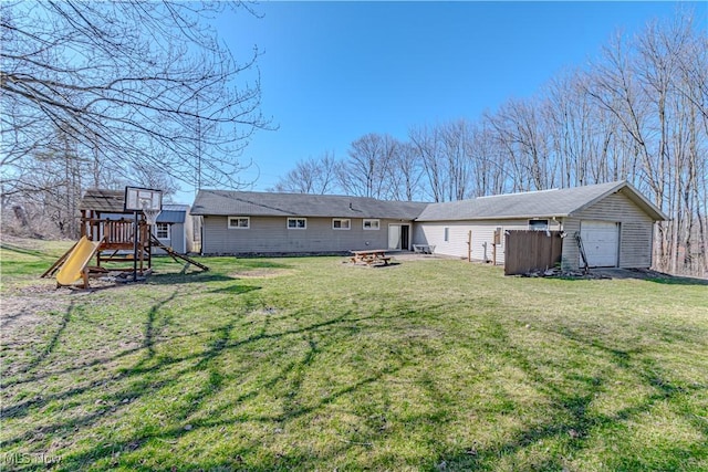 rear view of house with a playground, a yard, and an outdoor fire pit