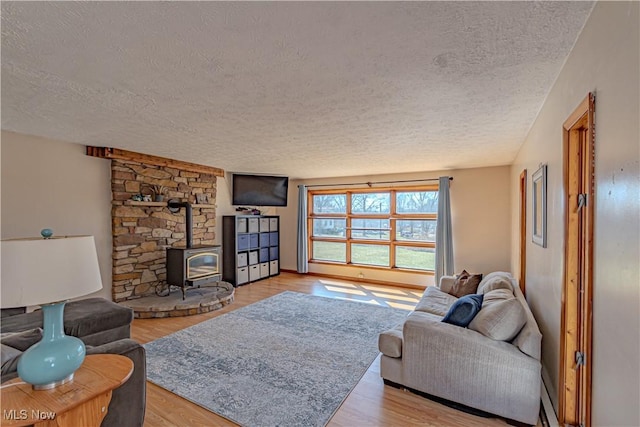 living room featuring a textured ceiling, a wood stove, and wood finished floors