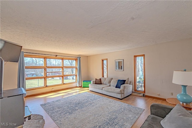 living room with a textured ceiling, baseboards, and wood finished floors