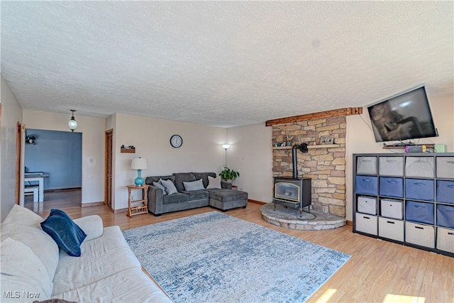 living room with a textured ceiling, wood finished floors, and a wood stove