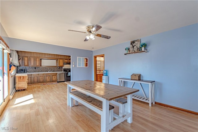 dining space with a ceiling fan, light wood-style floors, and baseboards