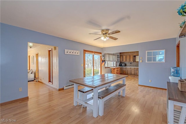 dining space featuring baseboard heating, baseboards, light wood-type flooring, and ceiling fan