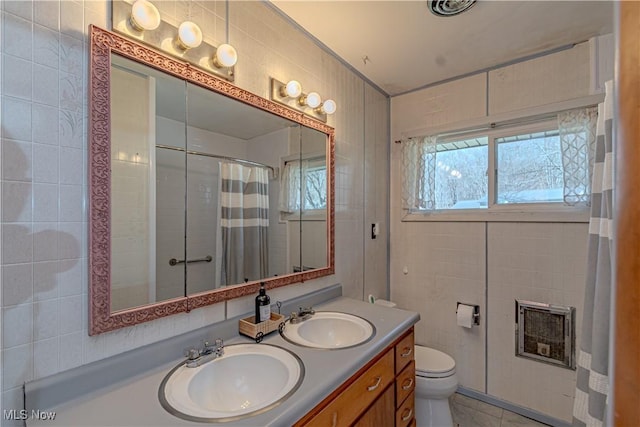 bathroom featuring tile patterned floors, toilet, tile walls, and a sink