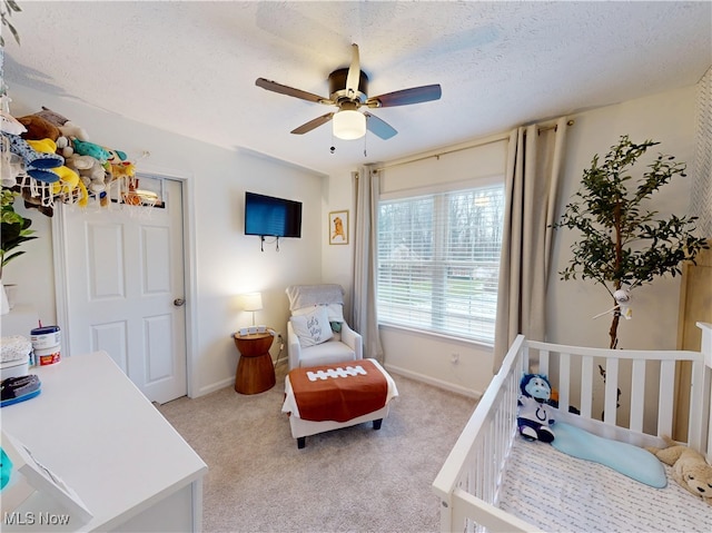 bedroom featuring baseboards, light colored carpet, and a textured ceiling