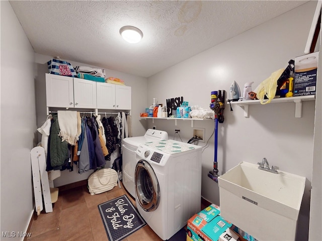 laundry area with a sink, a textured ceiling, cabinet space, separate washer and dryer, and tile patterned flooring